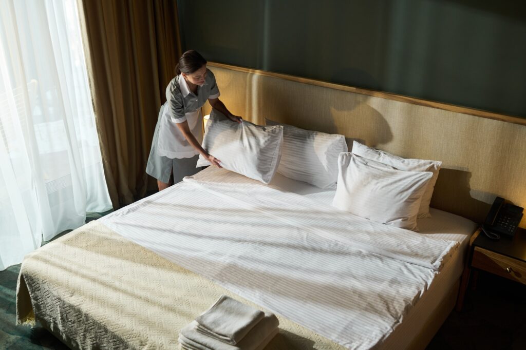 Housekeeper Making Bed in Hotel Room