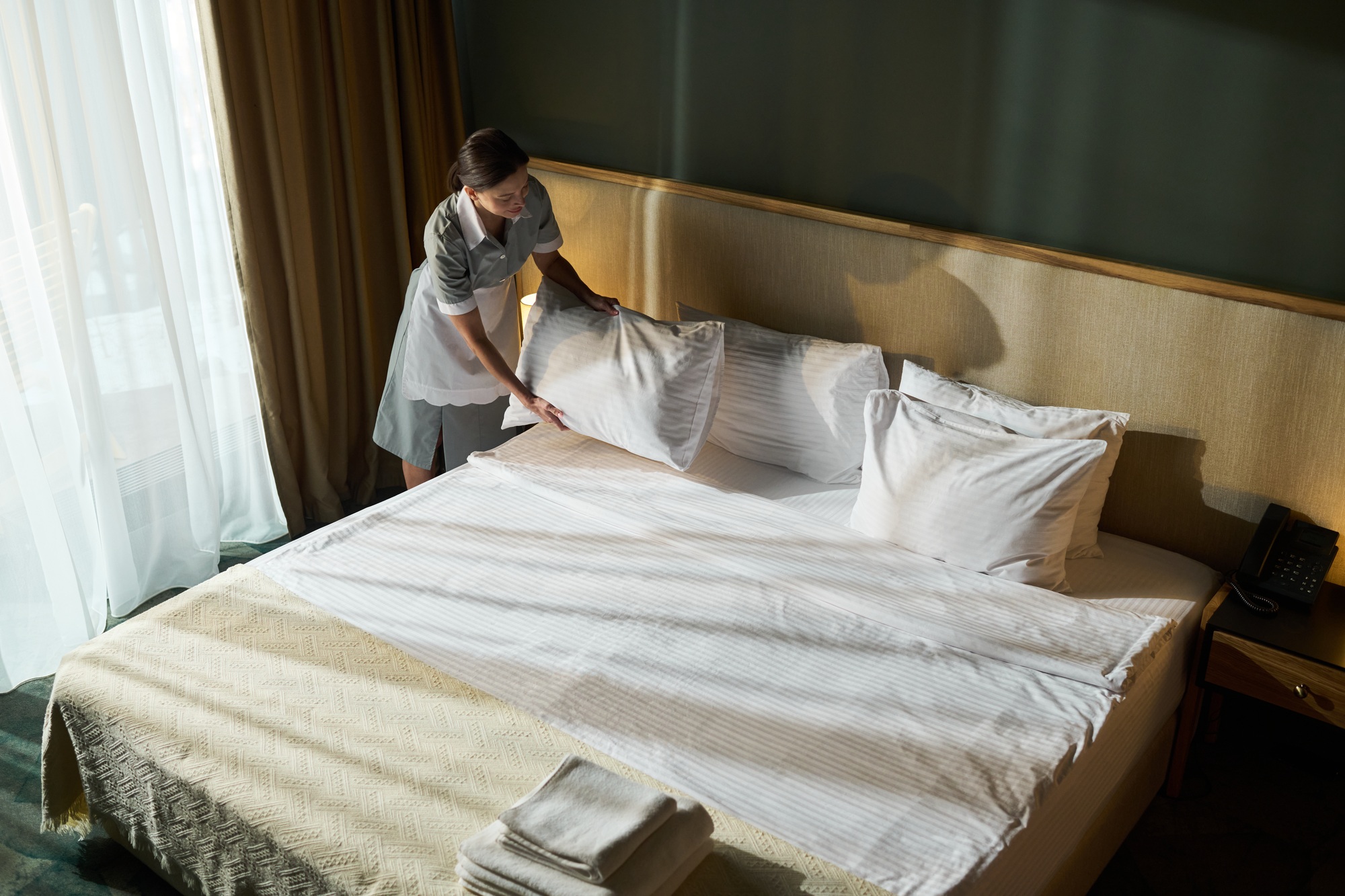 Housekeeper Making Bed in Hotel Room